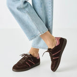 Brown and pink sneakers worn with light blue jeans on a white background
